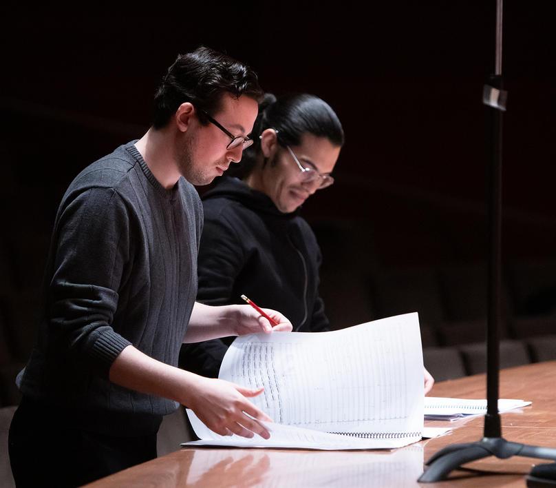 Student composers standing at rehearsal with music